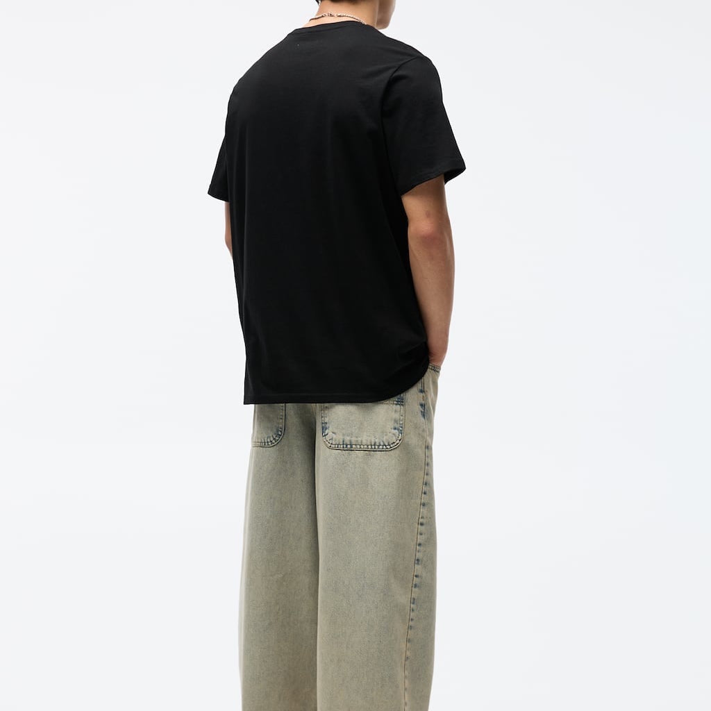 Person wearing a black t-shirt and light-colored jeans on a white background