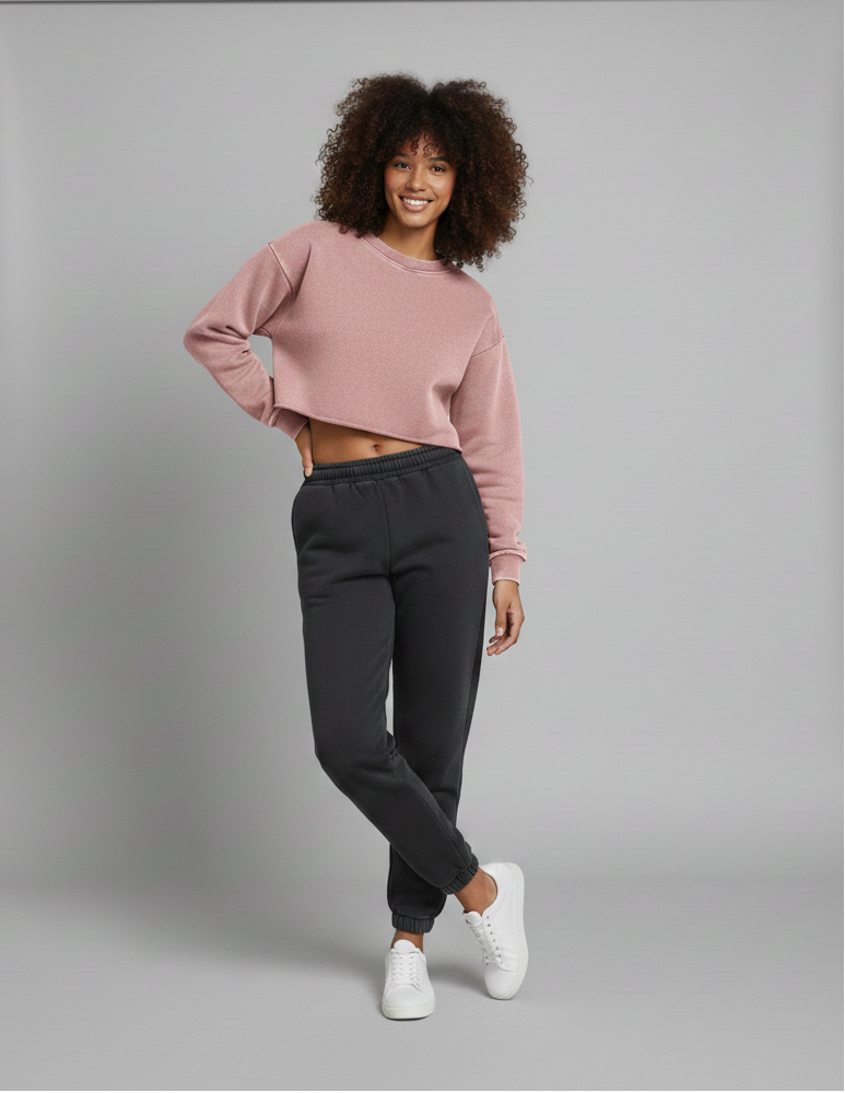 Woman wearing a pink sweater and black pants standing in front of a gray backdrop