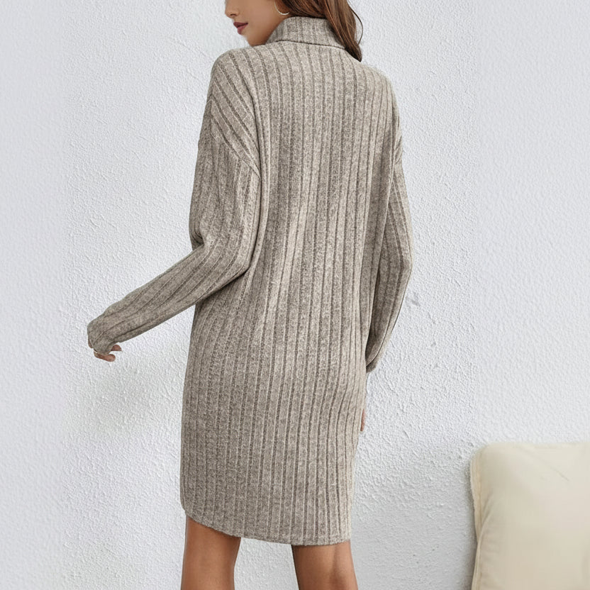 Person wearing a ribbed knit sweater dress against a white wall
