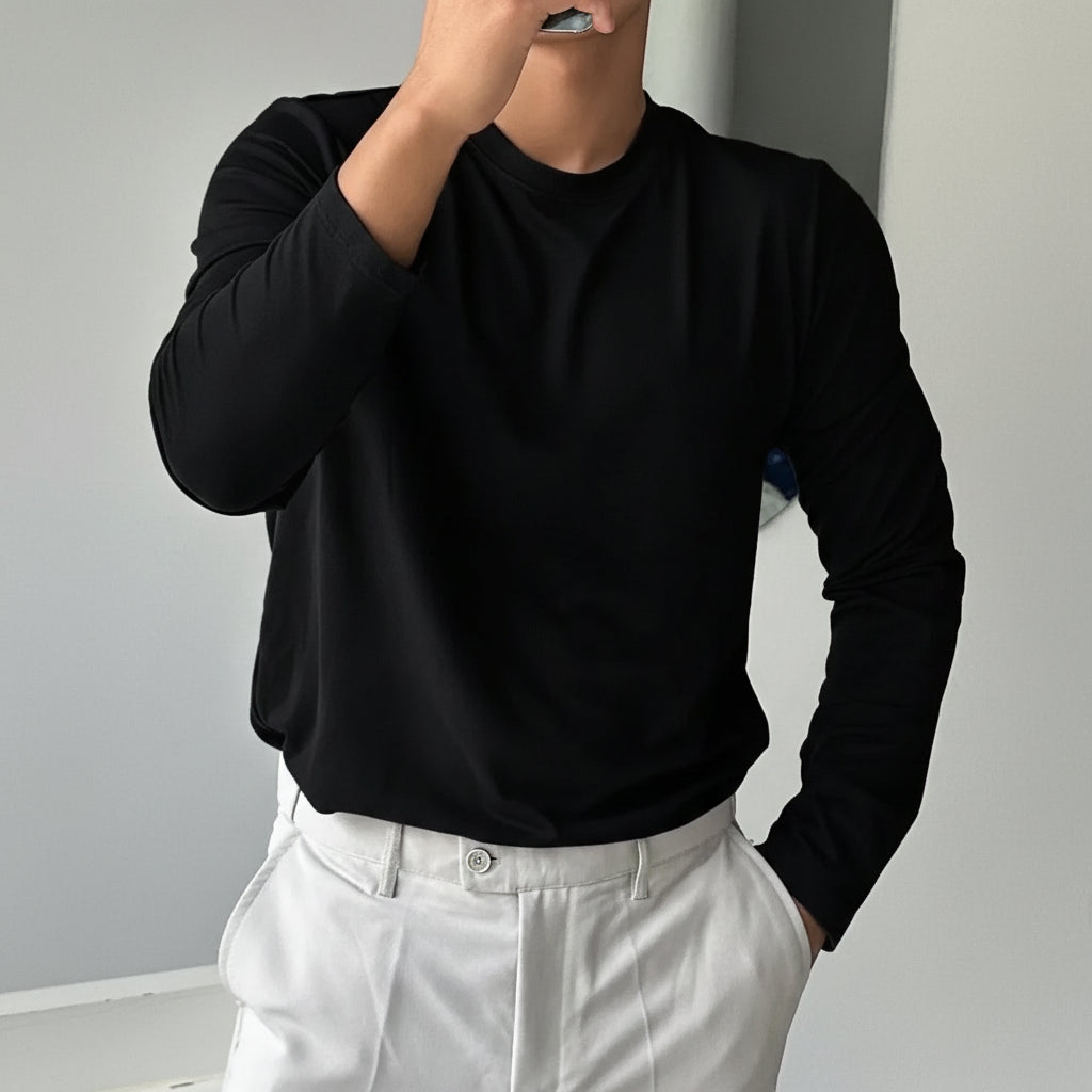 Person wearing a black sweater and white pants against a plain background