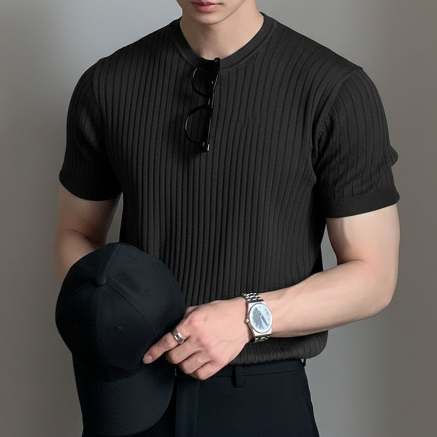 Person wearing a black ribbed sweater with a neutral background