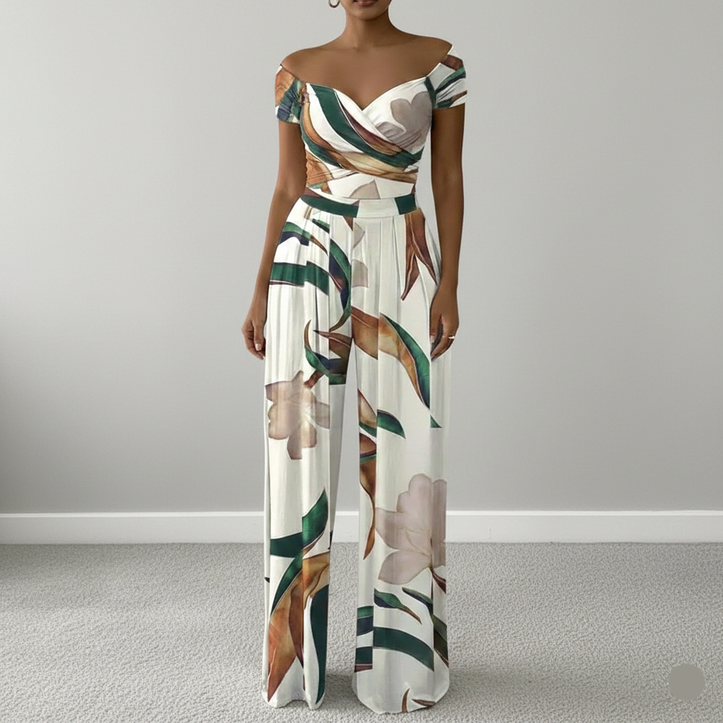 Woman wearing a floral off-shoulder jumpsuit on a plain background